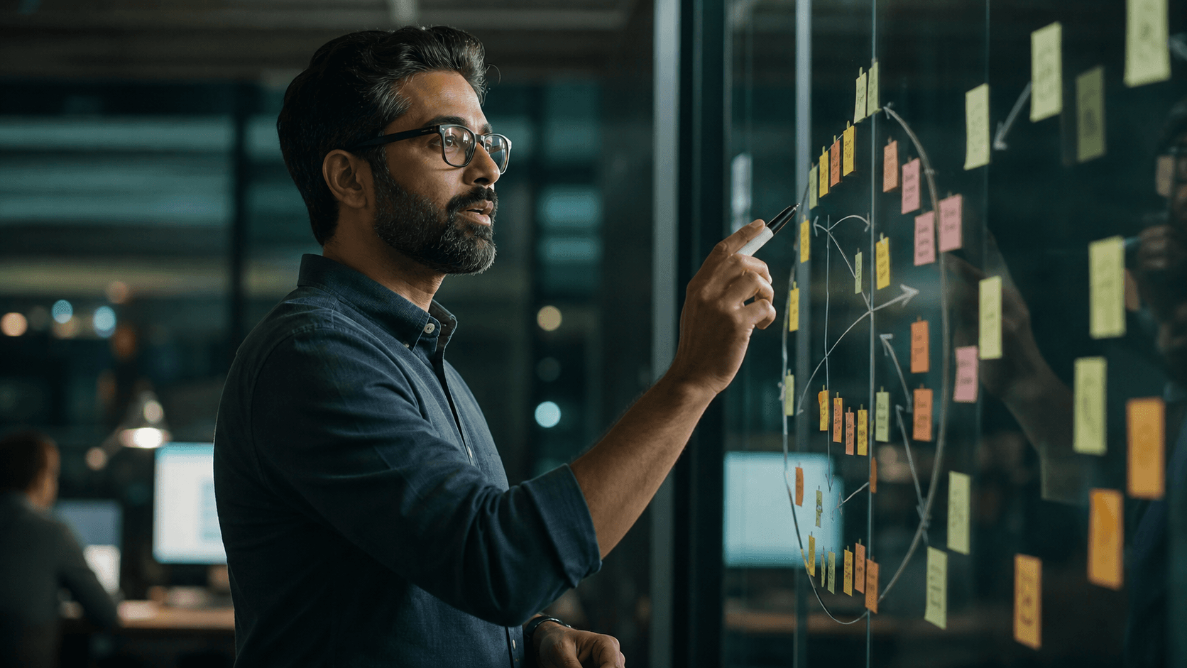 Engineering leader mapping a migration plan of sticky notes and arrows on a glass whiteboard in a dim office